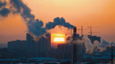 Sun sets behind apartment, multi-story buildings, smoking chimneys pollutes air Stock Footage 124685254
