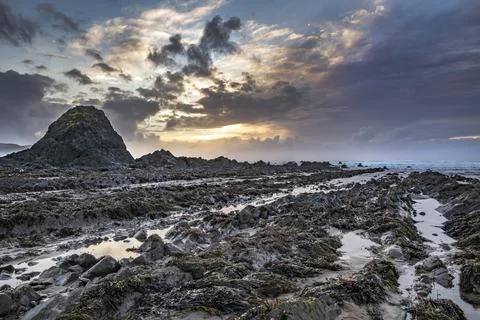 Sun sets behind Black Rock on Widemouth Bay beach Stock Photos