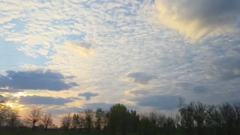 Sun sets behind clouds and trees with power lines. View from bus windiw. Stock Footage 331438374