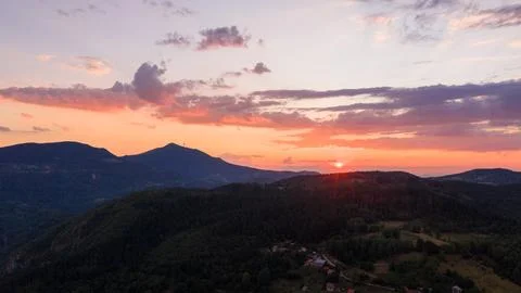 Sun sets behind distant ridges, painting the clouds with soft orange, pink, a Stock Photos