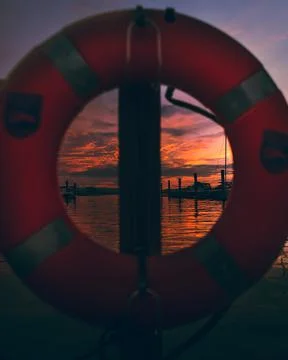The sun sets behind the docks as we look through the life preserver on the lake. Stock Photos