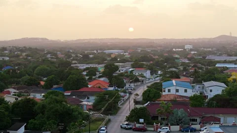 Sun sets behind hazey clouds on quiet edge of Caribbean neighborhood Stock Footage 270466713
