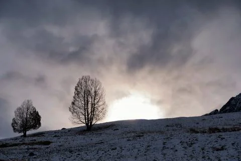 The sun sets behind a hilly landscape near Tarasp Stock Photos