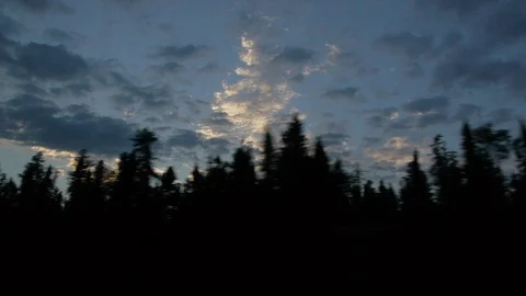 The Sun sets behind a line of Trees as the Train barrels past Stock Footage 92650810