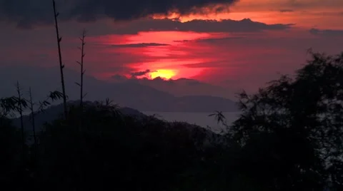 Sun sets behind mountain range time lapse trees in foreground 스톡 동영상 49957838