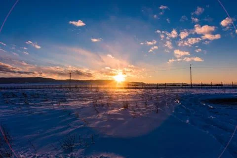 The sun sets behind the mountains and colors the clouds in winter, Altai, Rus Stock Photos