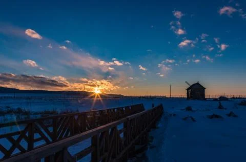 The sun sets behind the mountains and colors the clouds in winter, Altai, Rus Stock Photos