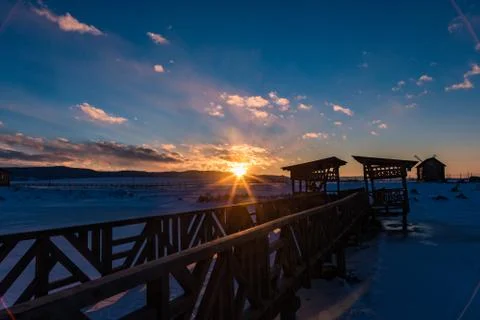 The sun sets behind the mountains and colors the clouds in winter, Altai, Rus Stock Photos
