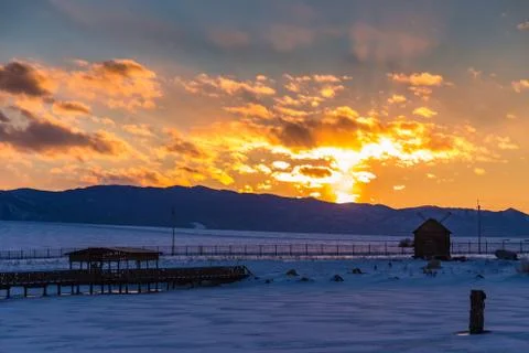 The sun sets behind the mountains and colors the clouds in winter, Altai, Rus Stock Photos