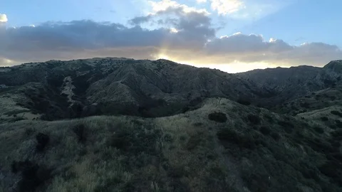 Sun sets behind the mountains with cloudy sky in the background Stock Footage 77662886