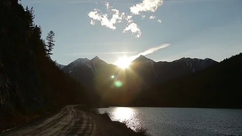 Sun sets behind mountains next to gravel road Stock Footage 72195331