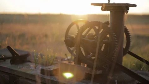 The sun sets behind rural machinery in a golden field in Alberta Video stock 90857346