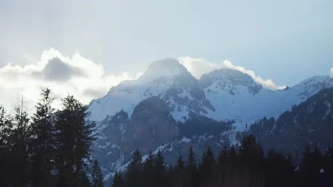 The sun sets behind the snow-covered mountains of the Alps, in Switzerland Stock Footage 239753816