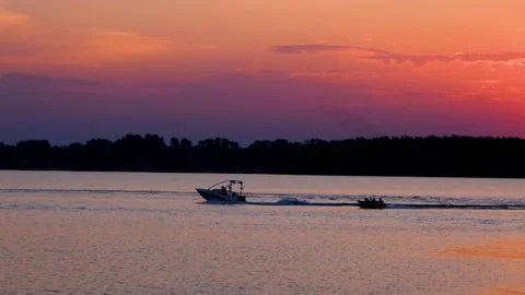 The sun sets below the horizon and is reflected in the lake. The bright orange Video stock 207409468