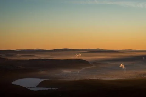 The sun sets below the horizon and illuminates Stock Photos