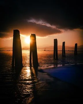 The sun sets between two pilons at the lake Stock Photos