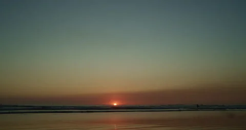 Sun sets into the distance below horizon line along beach 스톡 동영상 138316771