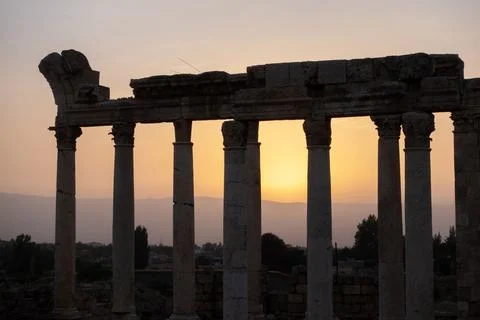 The sun sets gracefully behind the tall columns of ancient Baalbek, Lebanon. Stock Photos