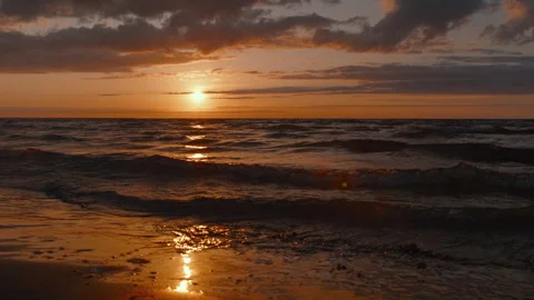 As the sun sets on the horizon, the tranquil sea waves shimmer in its fading Stock Footage 245283468