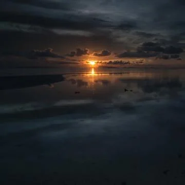 The sun sets over beach with beautiful reflection Stock Photos