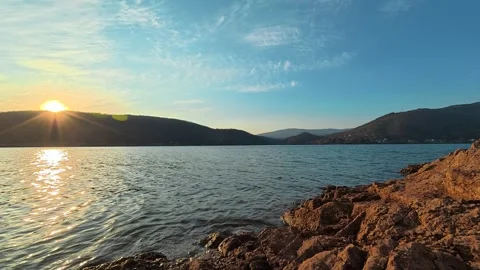 Sun sets over calm lake, casting golden glow . Bovan Lake Видео 330989031