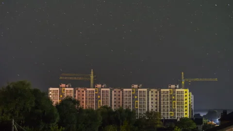 The sun sets over the construction site of a multi-story building and night Stock Footage 250524655