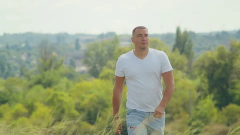 As the sun sets over the field, a man's open arms symbolize the freedom and Vídeos de archivo 248320391