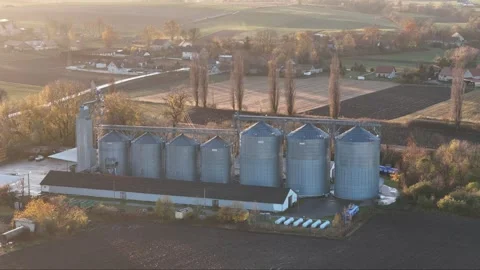 The sun sets over grain silos in a quaint village, casting a warm glow over.. Stock Footage 259229800
