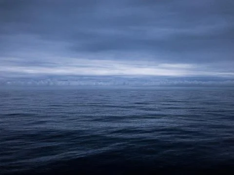 The sun sets over the horizon through clouds Stock Photos