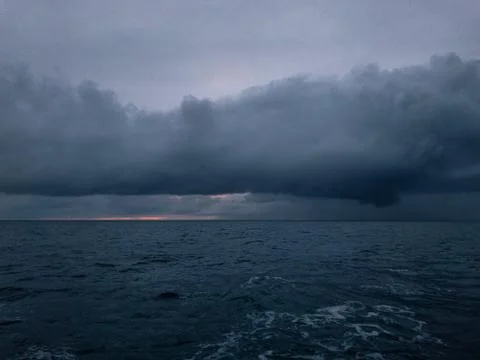 The sun sets over the horizon through clouds Stock Photos