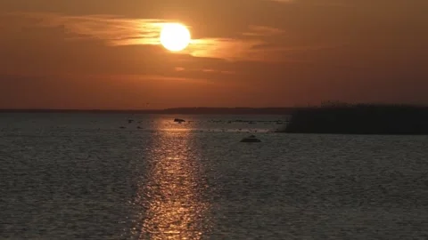 Sun sets over lake with light reflecting on water during evening hours Stock Footage 333446449