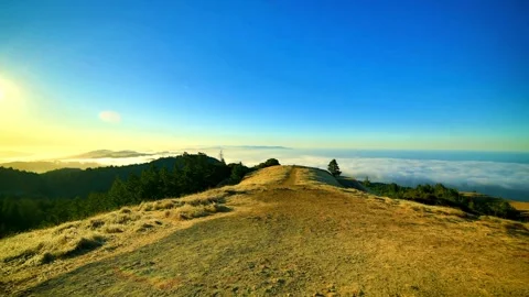 The sun sets over a mountain landscape with clouds on the horizon Stock Footage 312679524