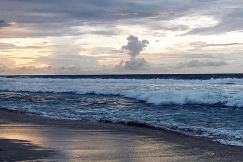 The sun sets over the ocean, casting golden hues across the waves. A dramatic Foto stock