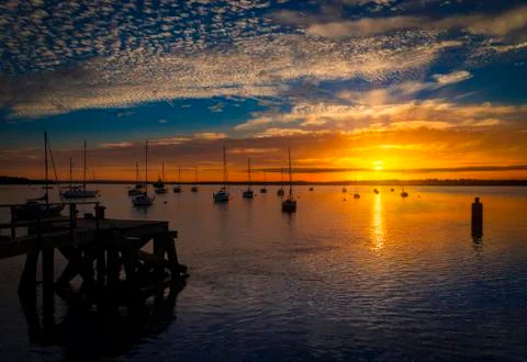 The Sun sets over Poole Harbour in Dorset. Hamworthy pier jetty Stock Photos