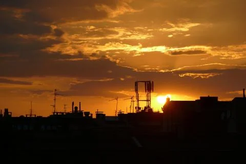 The sun sets over the rooftops in the city. Stock Photos