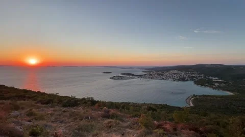 Sun sets over the sea and town, creating colorful sky at a coastal view point Stock Footage 339063575