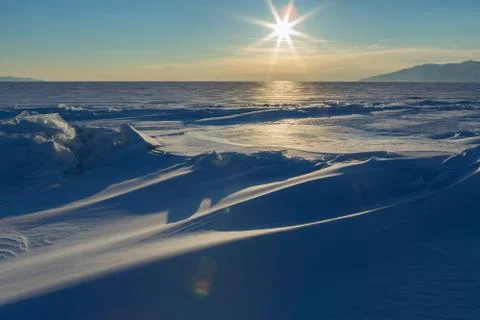 Sun sets over the snow-covered ice hummocks of Lake Baikal Stock Photos