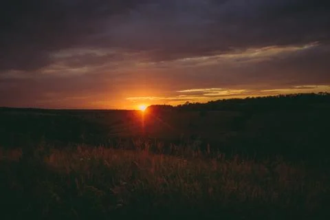 Sun sets over the tops of forest trees in clouds. Panoramic photo of purple Stock Photos