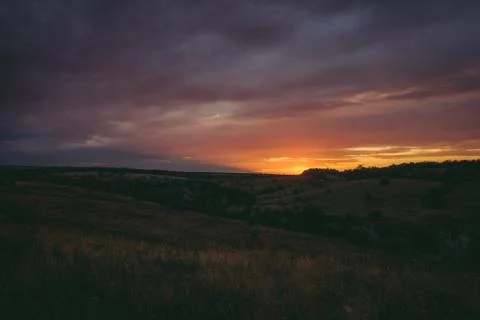 Sun sets over the tops of forest trees in clouds. Panoramic photo of purple Stock Photos