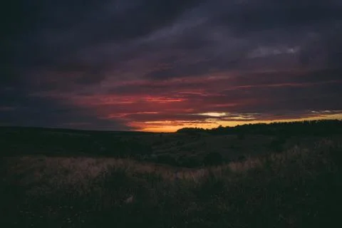 Sun sets over the tops of forest trees in clouds. Panoramic photo of purple Stock Photos