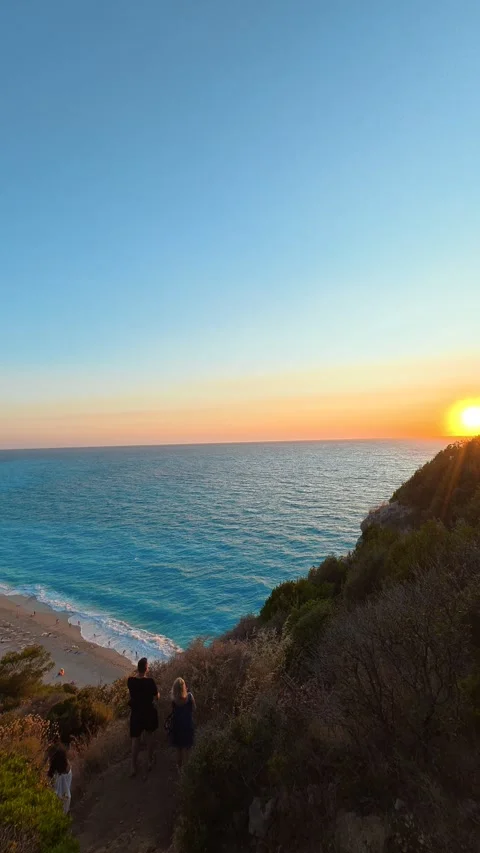 Sun sets over turquoise sea, casting golden glow. Milos Beach Greece Vertical Stock Footage 344169040