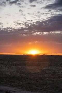 The sun sets over a vast field with a colorful sunset Stock Photos