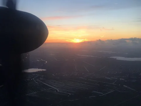 As the sun sets, a propeller plane, cruises over Amsterdam Airport (4K) Stock-Footage 79796410