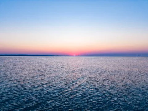 The sun sets slowly over the ocean. The sky changes colors as daylight fades  Stock Photos
