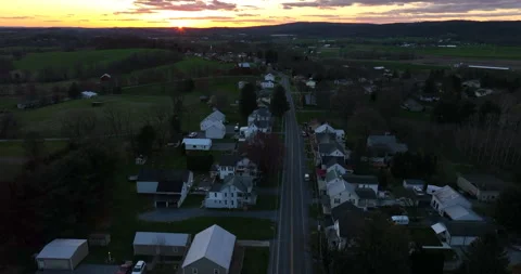Sun sets on small rural community in USA at night. Rising aerial with sun Stock Footage 182327814