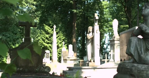 The sun sets on the stone statues in the old cemetery. Stone statue of a praying Stock Footage 130915909