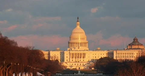 The sun sets at the US Capitol building in Washington, DC on a windy afternoon Stock Footage 148110546