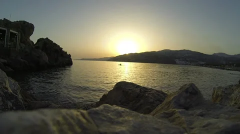 Sun sets while kayaker paddles in a bay and spanish music and children can be Stock Footage 30573836