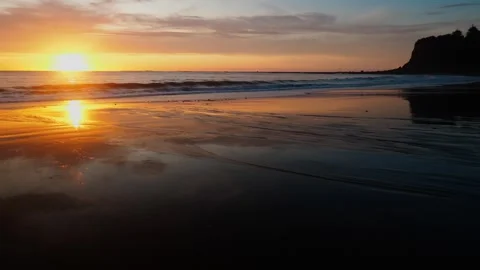 Sun setting on beach with cliffs 스톡 동영상 260370047