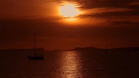 Sun setting behind beautiful clouds into the sea with sailing boats on the sea Stock-Footage 123086769